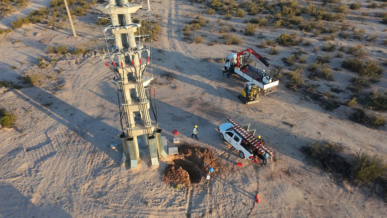 Equipo de trabajo montando estructura de línea eléctrica con camión grúa